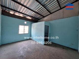 Empty room in a building with metal roofing and blue walls