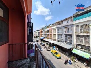 Outdoor view from a balcony overlooking a street with cars and buildings