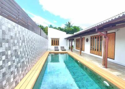 Outdoor pool area with wooden deck and lounge chairs