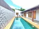 Outdoor pool area with wooden deck and lounge chairs