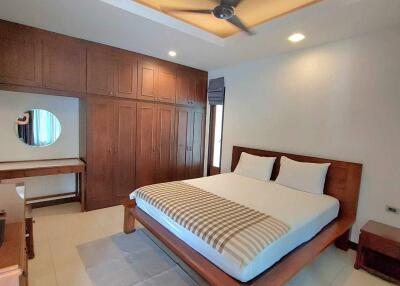 Spacious bedroom with bed, wooden wardrobe and ceiling fan