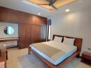 Spacious bedroom with bed, wooden wardrobe and ceiling fan