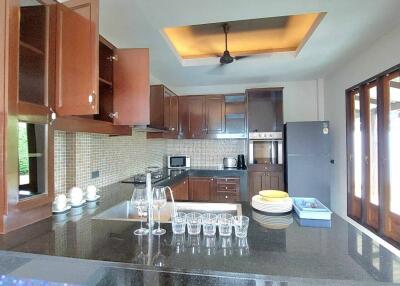 Modern kitchen with open cabinets, black granite countertops, and glassware