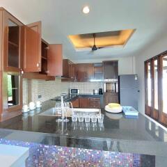 Modern kitchen with open cabinets, black granite countertops, and glassware