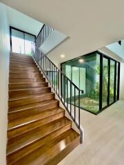 Modern stairway with wooden steps and glass-enclosed garden area