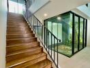 Modern stairway with wooden steps and glass-enclosed garden area