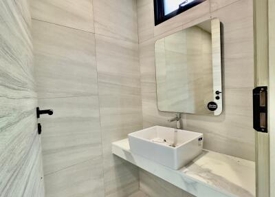 Modern bathroom with minimalist design featuring a wall-mounted sink and a large mirror