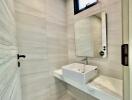 Modern bathroom with minimalist design featuring a wall-mounted sink and a large mirror