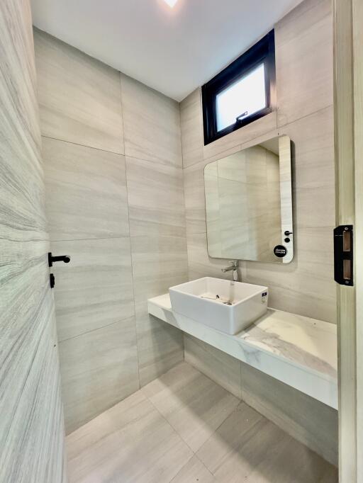 Modern bathroom with minimalist design featuring a wall-mounted sink and a large mirror