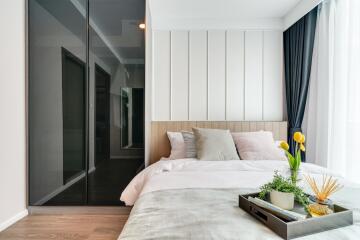 Modern bedroom with large mirrors, bed, and decorative plants