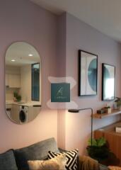 Modern living room with mirror, wall art, and a glimpse of the adjacent kitchen