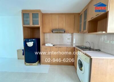 Modern kitchen with wooden cabinets, refrigerator, sink, and washing machine