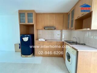 Modern kitchen with wooden cabinets, refrigerator, sink, and washing machine