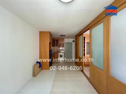 View of the kitchen area with wooden cabinetry, washing machine and sliding doors.