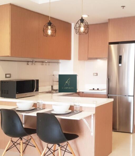 Modern kitchen with wooden cabinets, stainless steel appliances, and a breakfast bar