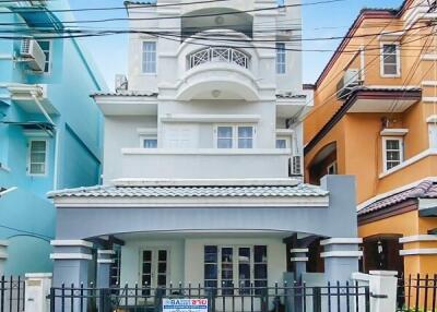 Exterior view of a three-story house with a gated entrance