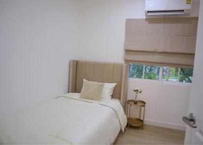 Small bedroom with bed, window, side table and air conditioning