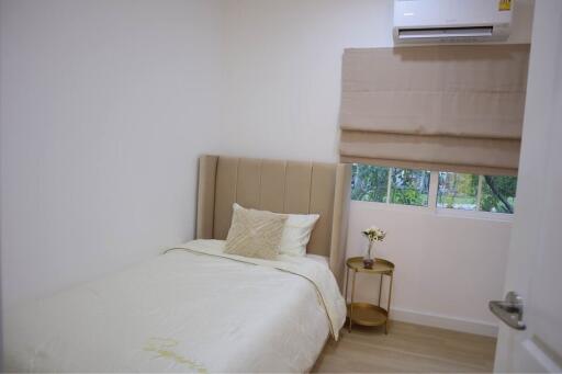 Small bedroom with bed, window, side table and air conditioning