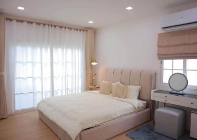 Spacious bedroom with a large bed, side table, dressing table, and air conditioner.