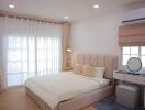 Spacious bedroom with a large bed, side table, dressing table, and air conditioner.