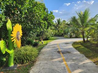 A scenic outdoor pathway surrounded by lush greenery and a sunflower sculpture