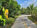 A scenic outdoor pathway surrounded by lush greenery and a sunflower sculpture