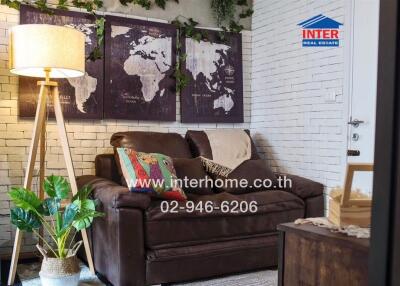 Cozy living room with a leather sofa, world map wall art, and floor lamp