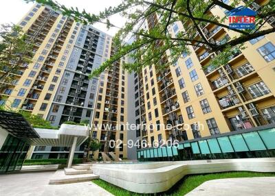 Exterior view of a multi-story residential building with balconies and ground-level amenities