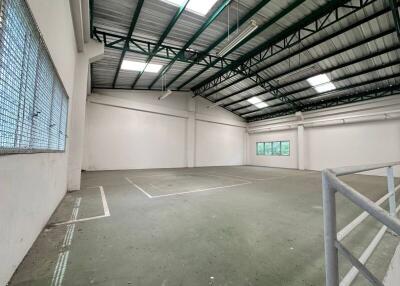 Spacious interior of an industrial building with a high ceiling and large windows.