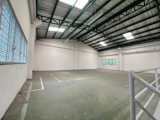 Spacious interior of an industrial building with a high ceiling and large windows.