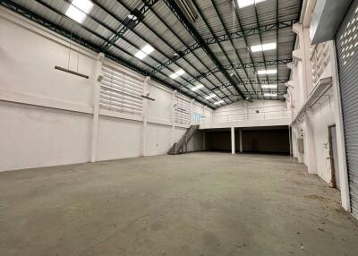 Interior of a large empty industrial warehouse with high ceilings and mezzanine