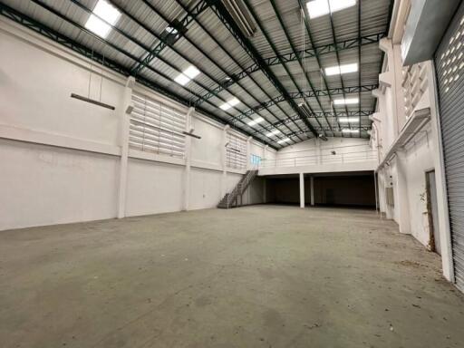 Interior of a large empty industrial warehouse with high ceilings and mezzanine