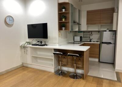 Modern kitchen with barstools, TV, and appliances