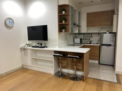 Modern kitchen with barstools, TV, and appliances