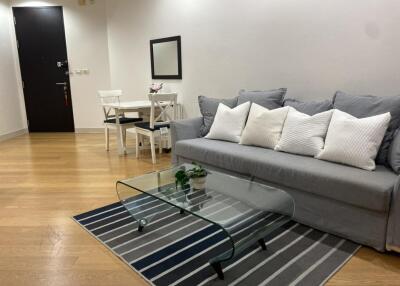 Living room with grey sofa, glass coffee table, and dining set