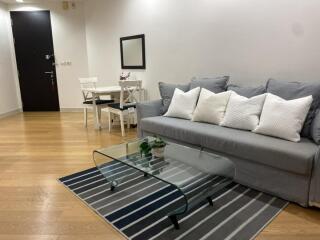 Living room with grey sofa, glass coffee table, and dining set