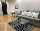 Living room with grey sofa, glass coffee table, and dining set