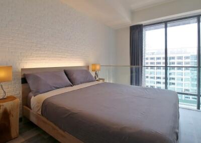 Modern bedroom with brick accent wall and large windows