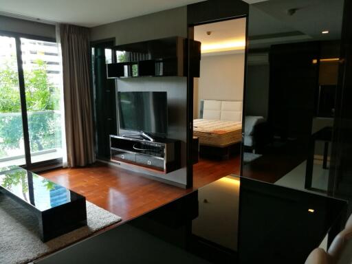 Modern living room with TV and a view into the bedroom