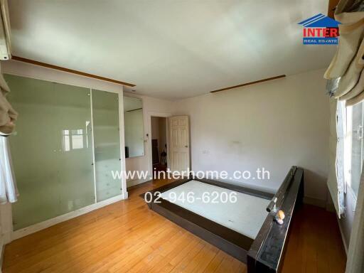 Spacious unfurnished bedroom with wooden flooring and glass-paneled closet