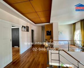 Spacious hallway with wooden flooring and ceiling, featuring access to multiple rooms and a staircase