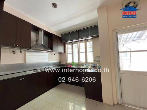 Modern kitchen with dark cabinets, stainless steel appliances, and a large window