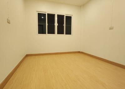 Well-lit empty bedroom with wooden floor and white walls