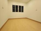 Well-lit empty bedroom with wooden floor and white walls