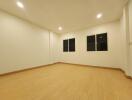 Spacious unfurnished living room with wooden flooring and recessed lighting