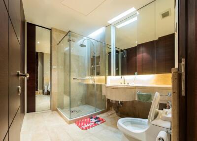 Modern bathroom with glass shower enclosure, floating sink, and toilet