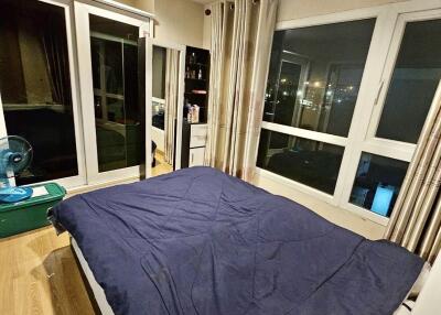 Bedroom with large windows, curtains, and blue bedding