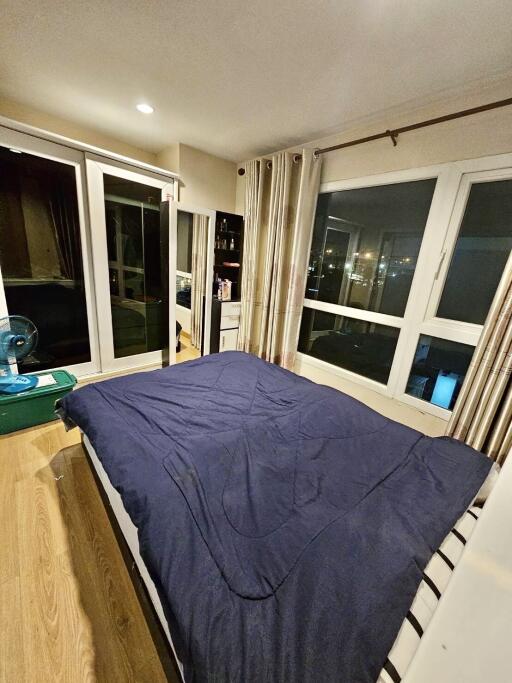 Bedroom with large windows, curtains, and blue bedding