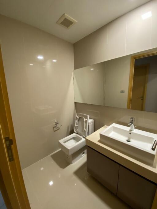 Modern bathroom with sink, toilet, and large mirror