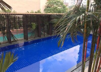 Swimming pool area with greenery and buildings in background